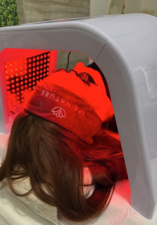 Cliente em sessão de fototerapia LED, usando a máscara de descanso bordô da marca