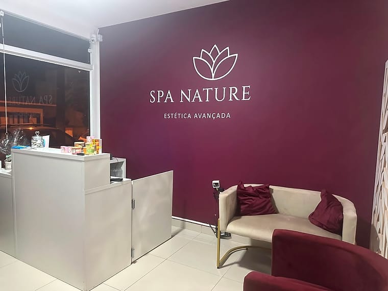 Recepção da SPA Nature Tijucas, com balcão branco e a marca aplicada na parede bordô